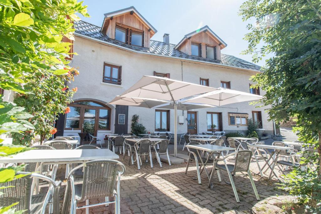 um grupo de mesas e cadeiras com guarda-sóis em frente a um edifício em Auberge Le Vieux Chaillol em Saint-Michel-de-Chaillol