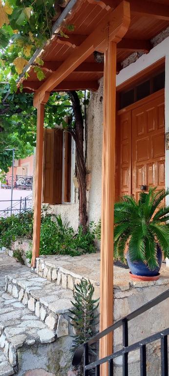 uma pérgola de madeira com dois vasos de plantas em frente a uma casa em Maroudas Traditional Guest House em Vathi