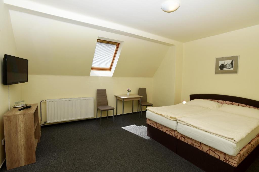 a bedroom with a bed and a tv and a table at Hotel U Jezírka in Liberec