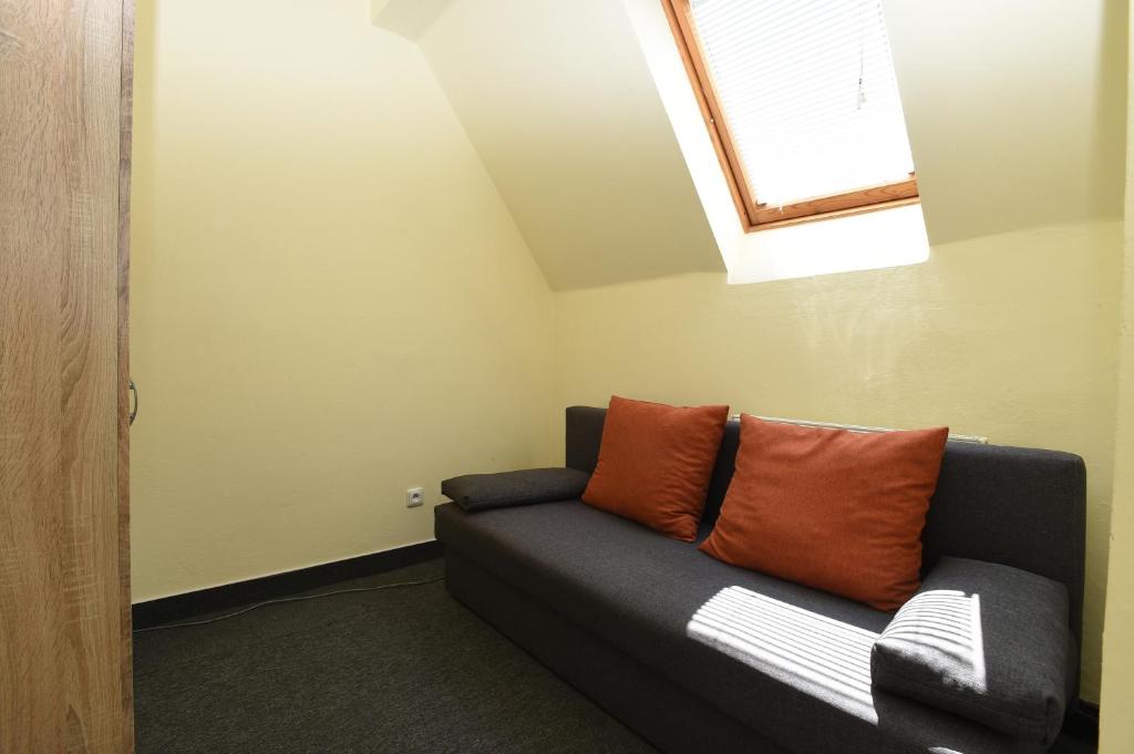 a couch with two orange pillows in a room at Hotel U Jezírka in Liberec