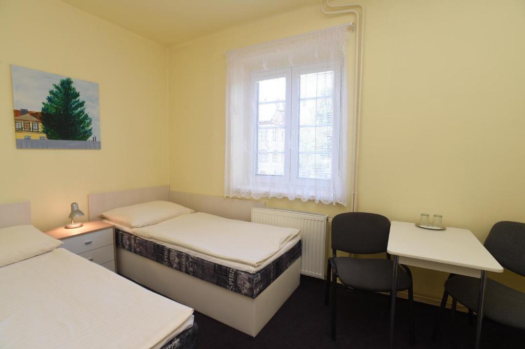 a room with two beds and a window and a table and chairs at Hotel U Jezírka in Liberec