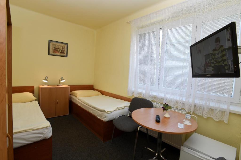 a room with two beds and a table and a tv at Hotel U Jezírka in Liberec