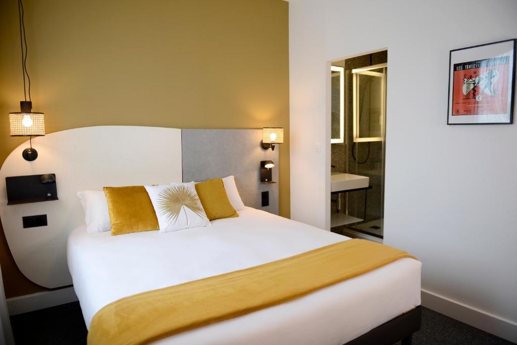 Cette chambre d'hôtel dispose d'un grand lit blanc avec des oreillers en or. dans l'établissement Hôtel Villa Berlioz, à Lyon