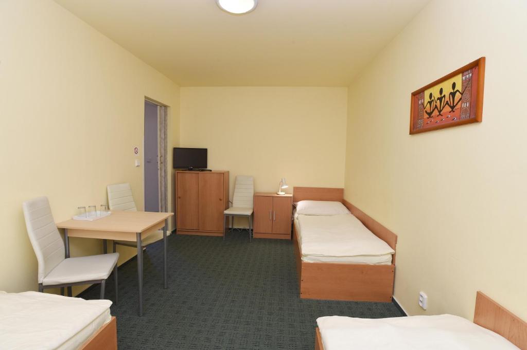 a room with two beds and a table and chairs at Hotel U Jezírka in Liberec