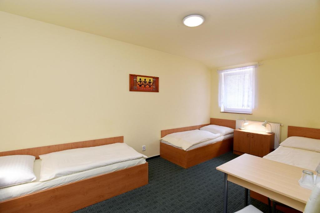 a small room with two beds and a table at Hotel U Jezírka in Liberec