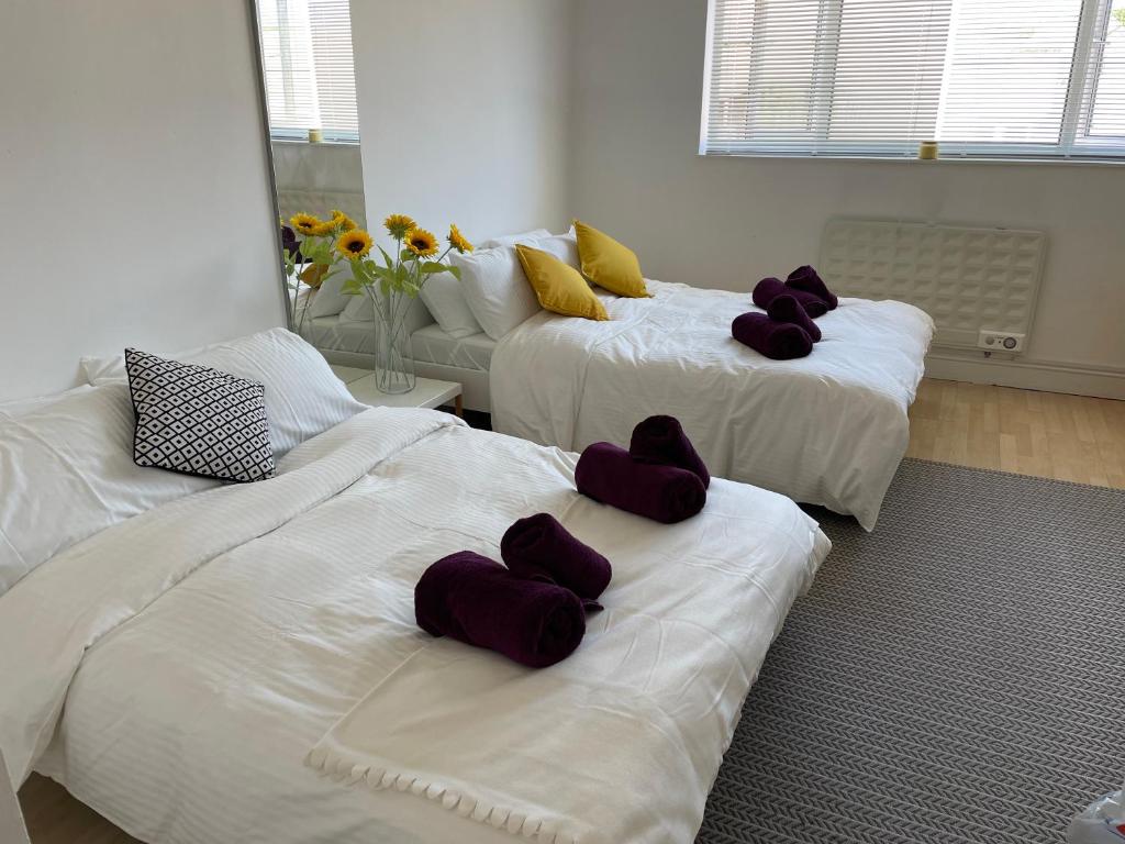 three beds with purple pillows on them in a room at Holiday Home Fulham in London