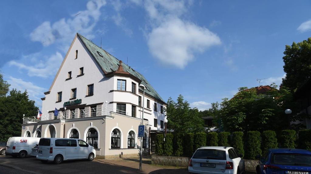 a white building with cars parked in front of it at Hotel U Jezírka in Liberec