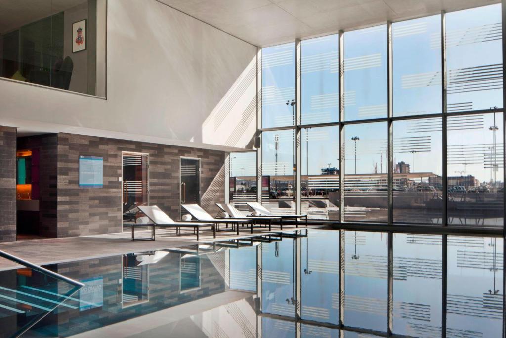 a lobby with chairs and a pool of water at Aloft London Excel in London