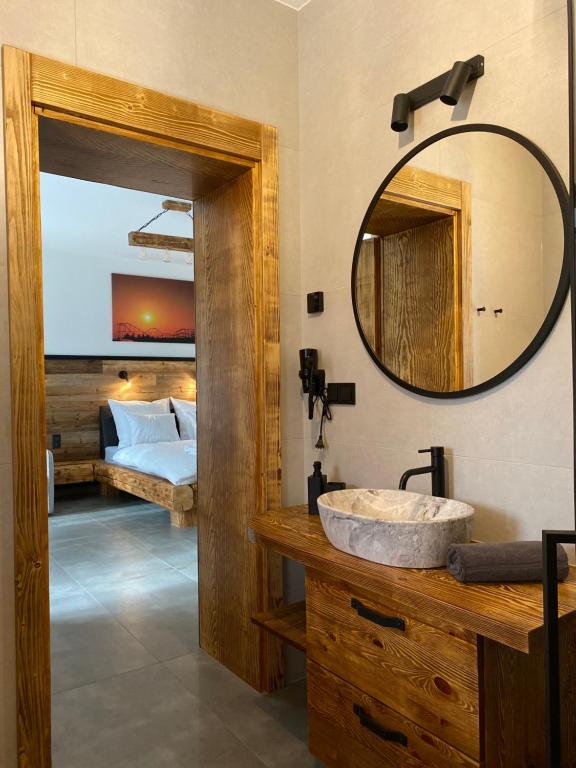 een badkamer met een wastafel, een spiegel en een bed bij Apartamenty Zander in Zator