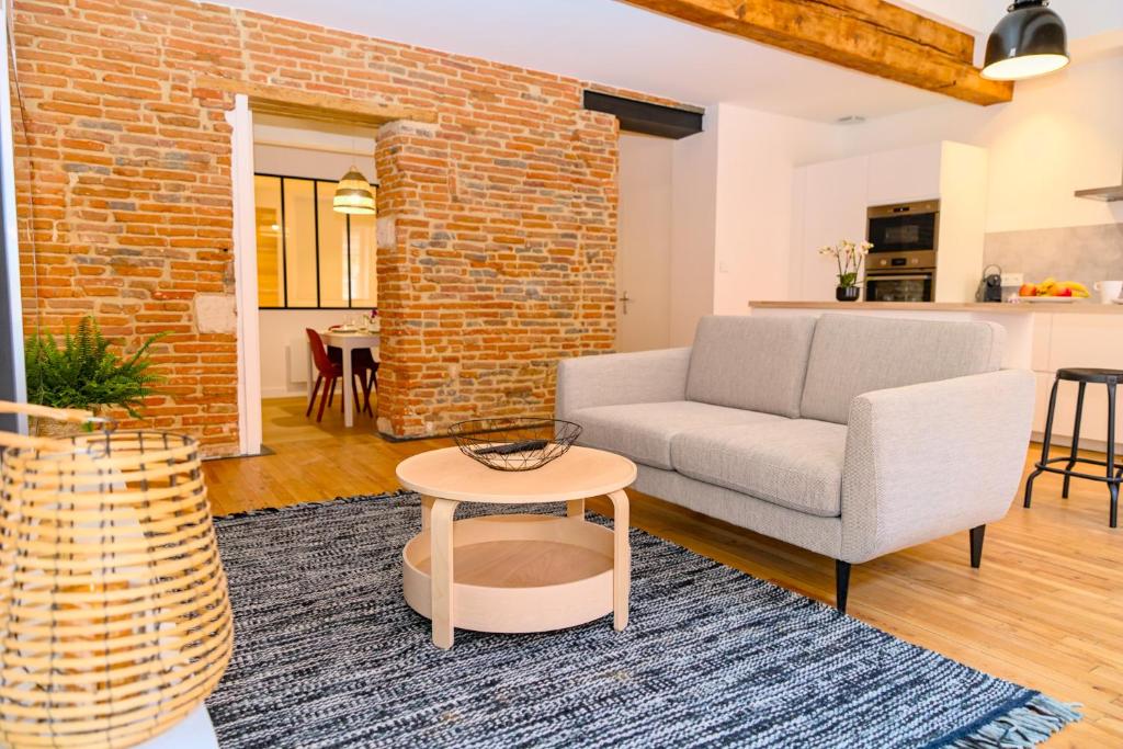 a living room with a couch and a brick wall at Le Saint Rome - Toulouse Hypercentre in Toulouse