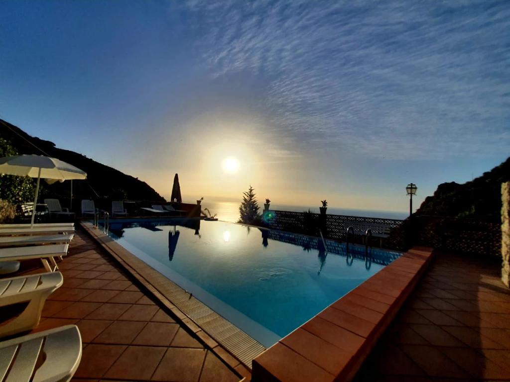 una piscina con il tramonto sull'oceano di VILLA ZEN TAORMINA a Taormina