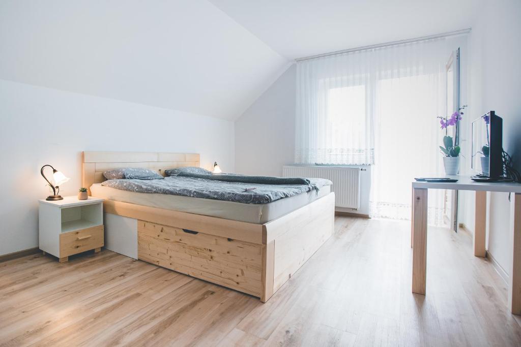 a white bedroom with a bed and a wooden floor at Apartma pri Boštjanu in Škofja Loka