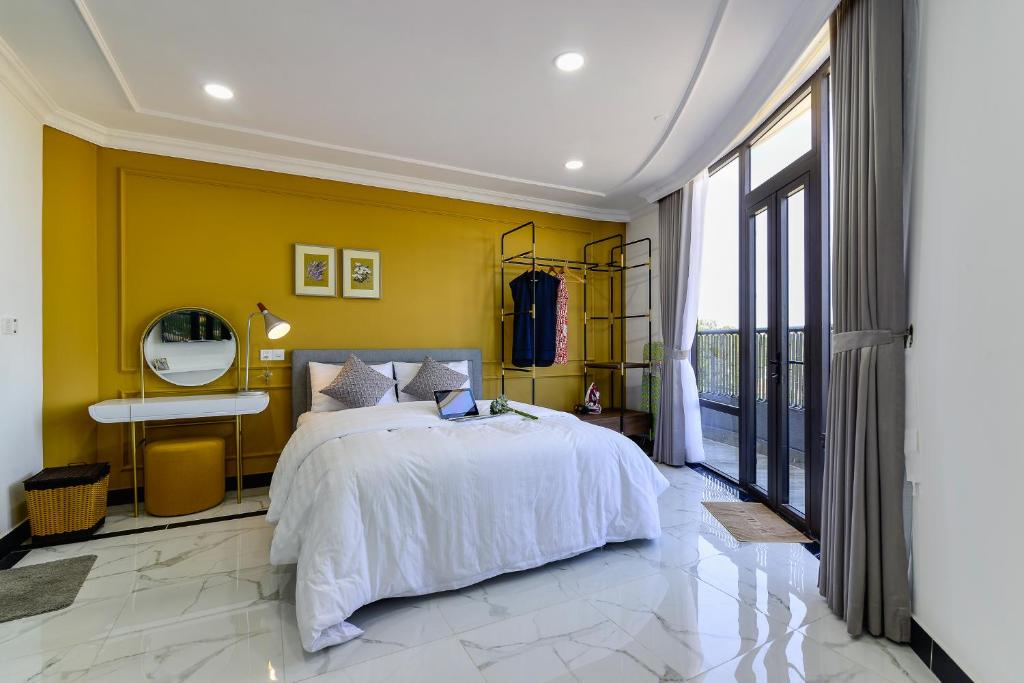 a bedroom with a bed and a yellow wall at Aura Apartment Da Lat in Da Lat