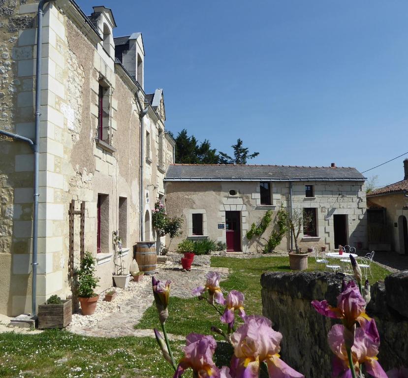 stary kamienny dom z kwiatami na dziedzińcu w obiekcie Le Clos de La Pinsonnière w mieście Vaudelnay