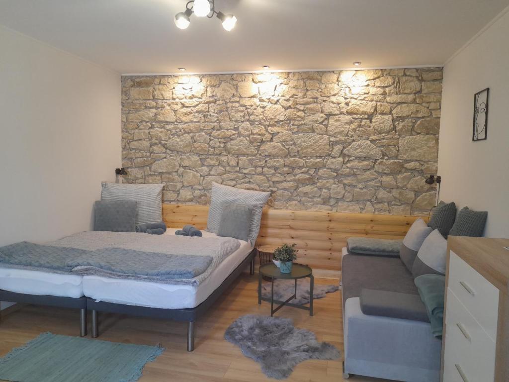 1 dormitorio con cama y pared de piedra en Kaland apartman II., en Sátoraljaújhely