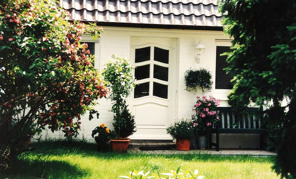 una casa blanca con flores delante en Heide Apartments, en Schneverdingen