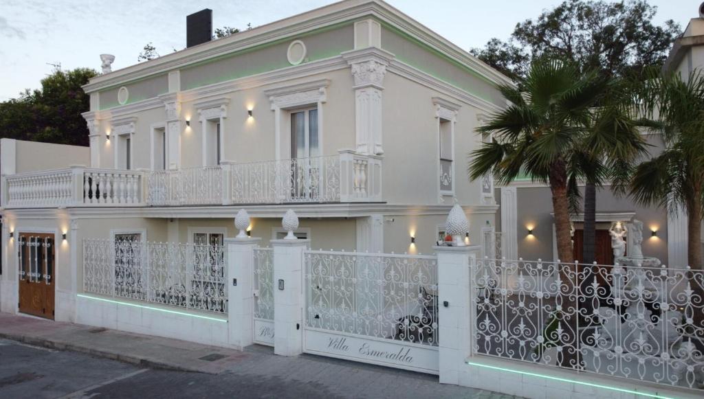 una casa blanca con una valla blanca y una palmera en B&B Villa Esmeralda en San Filippo del Mela