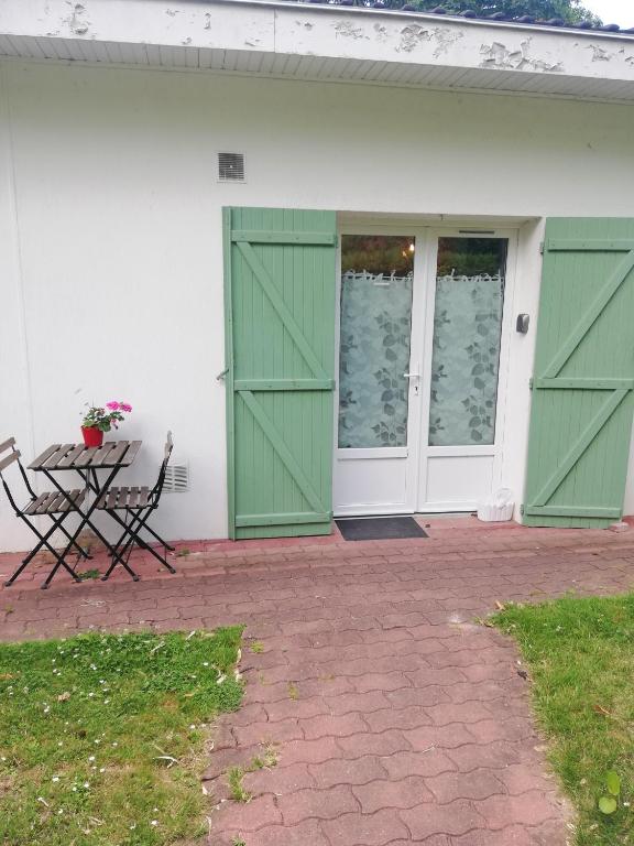 une maison blanche avec des portes vertes et une table dans l'établissement Appartement de plain pied dans la verdure, à Yerres