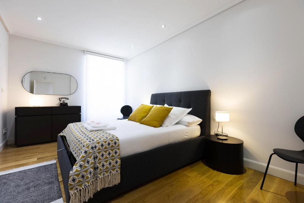 - une chambre avec un lit doté d'oreillers jaunes et d'un miroir dans l'établissement Haizea by Smiling Rentals, à Fontarrabie