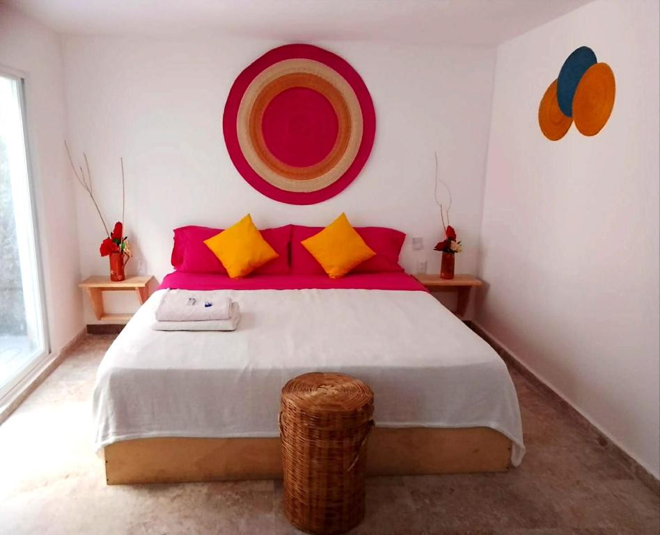 a bedroom with a large bed with red and yellow pillows at Casa Isabella in Cozumel