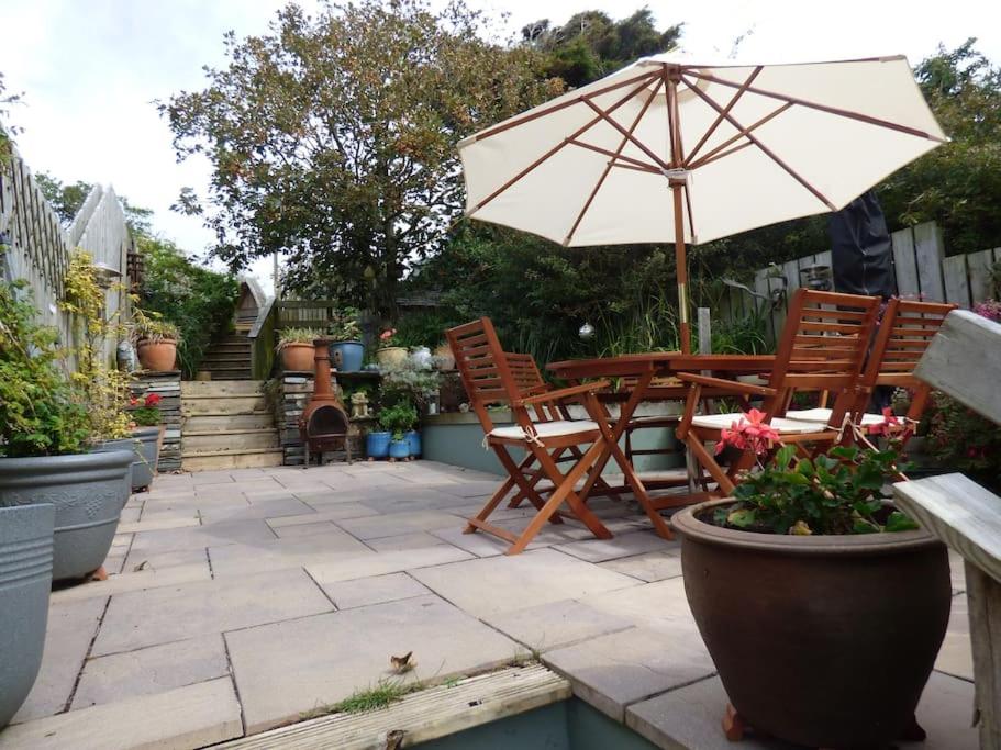 a patio with a table and chairs and an umbrella at Trelake Cottage in Tintagel