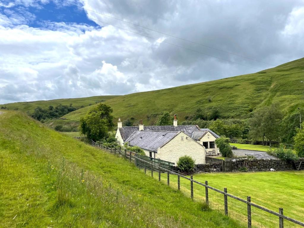 a house in the middle of a green hill at Pass the Keys Beautiful Scottish Cottage in Outstanding Location in Sanquhar