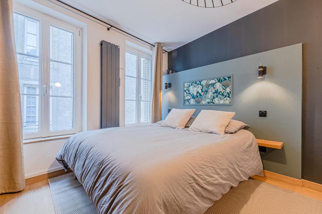 ein Schlafzimmer mit einem großen Bett und zwei Fenstern in der Unterkunft La Suite Cathédrale in Metz