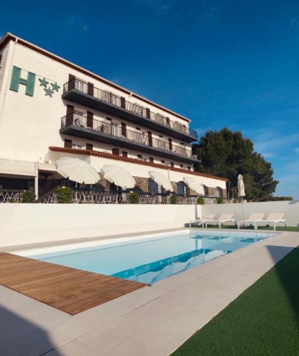 a hotel with a swimming pool in front of a building at Hôtel Le Belvedere in Saint-Cyprien
