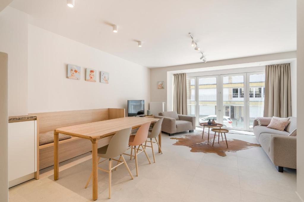 een keuken en een woonkamer met een houten tafel en stoelen bij Appartement luxueus én op 1 min van het strand in Koksijde