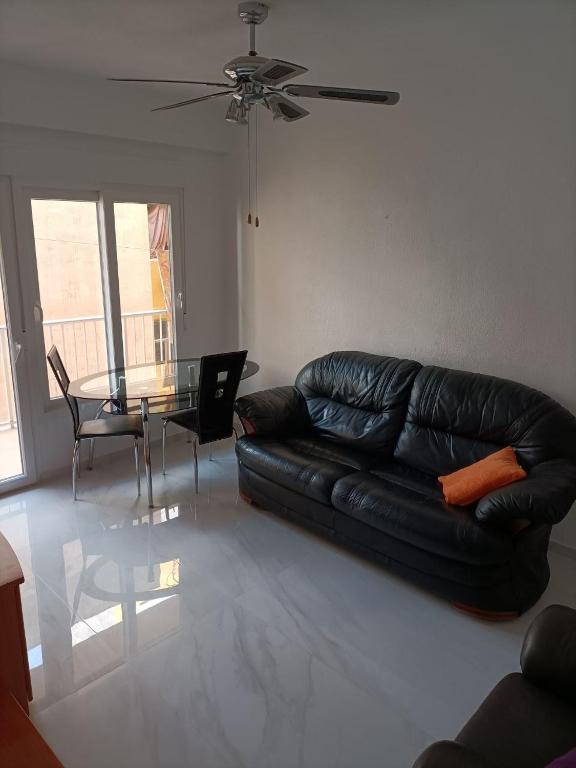 uma sala de estar com um sofá de couro preto e uma mesa em Bergantin 8 em Torrevieja