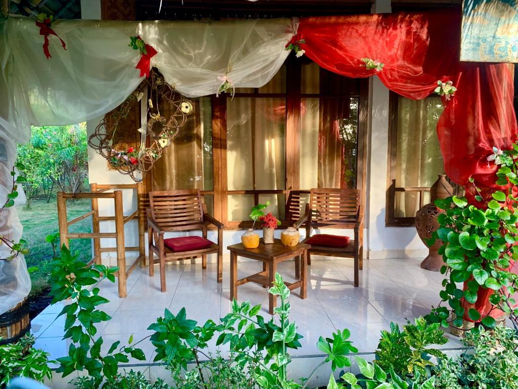 a patio with chairs and a table and a curtain at Budi Sun Resort in Maumere