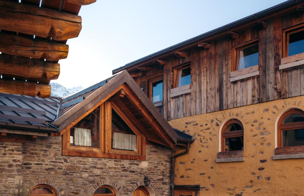 un edificio de madera con ventanas y techo en Agriturismo Belotti en Temù