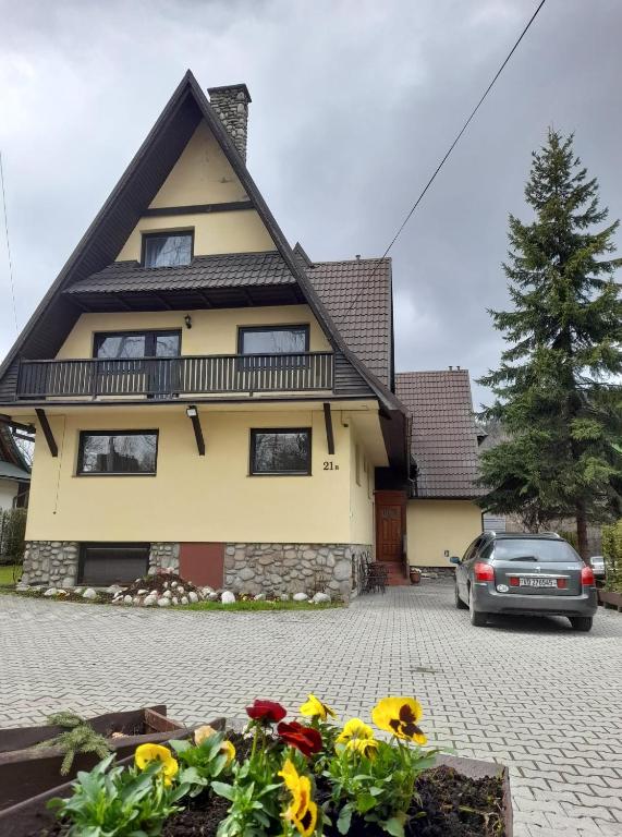 une maison jaune avec des fleurs devant elle dans l'établissement Apartament u Micka Poronin 5 km od Zakopanego, à Poronin