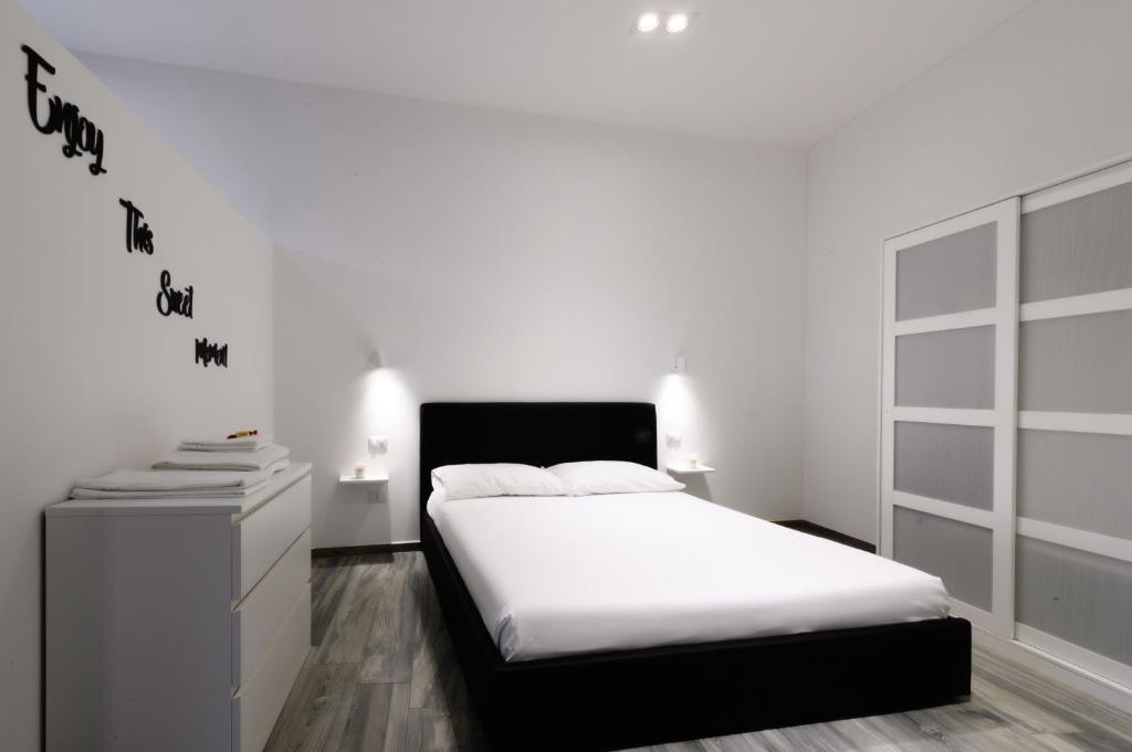 ein weißes Schlafzimmer mit einem Bett und einer Kommode in der Unterkunft Loft San Vitale in Ravenna