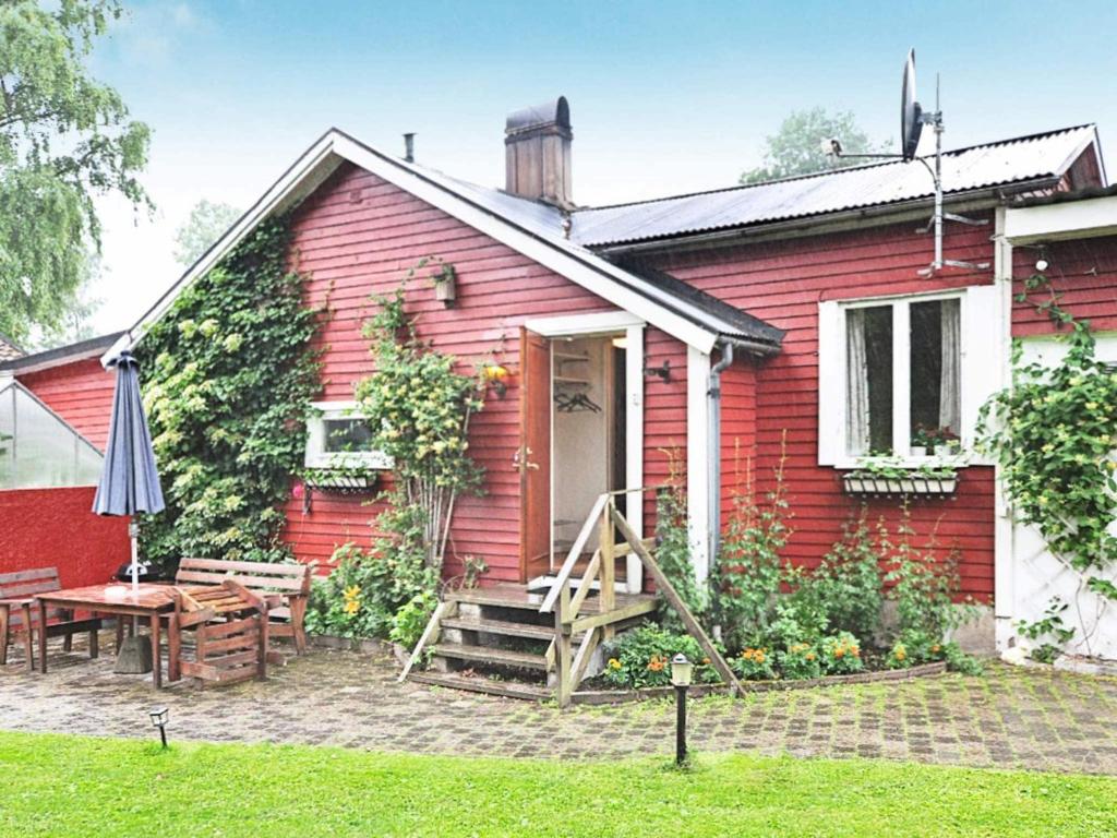 a red house with a table and an umbrella at 5 person holiday home in H SSLEHOLM in Hässleholm