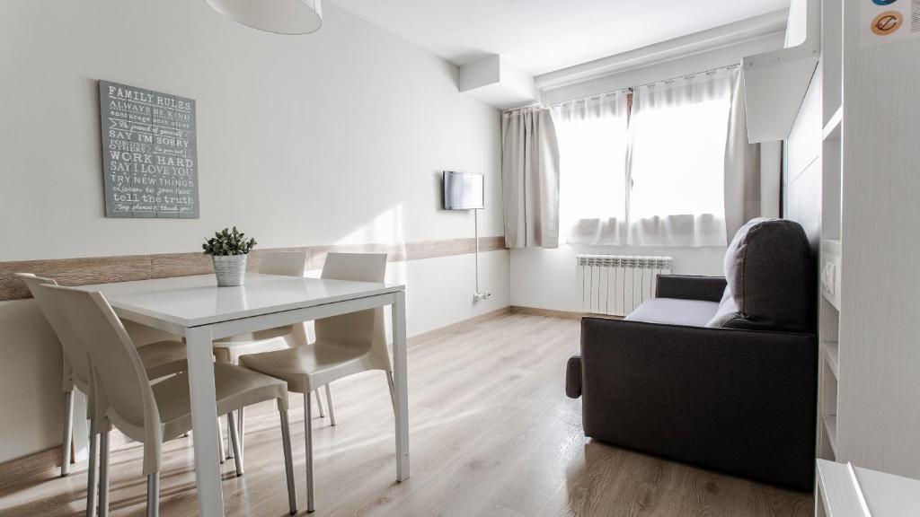 - une salle à manger blanche avec une table et des chaises blanches dans l'établissement Outdoor Apartaments - Basecamp, à Andorre-la-Vieille