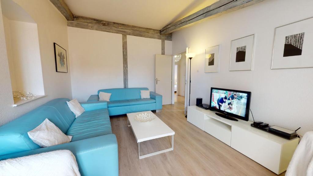 a living room with a blue couch and a tv at Tel un songe blanc in Colmar