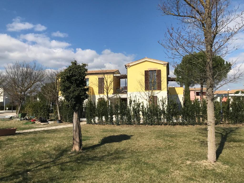une maison jaune dans une cour avec deux arbres dans l'établissement Nella natura a due passi dal mare a casa di Francy, à Numana