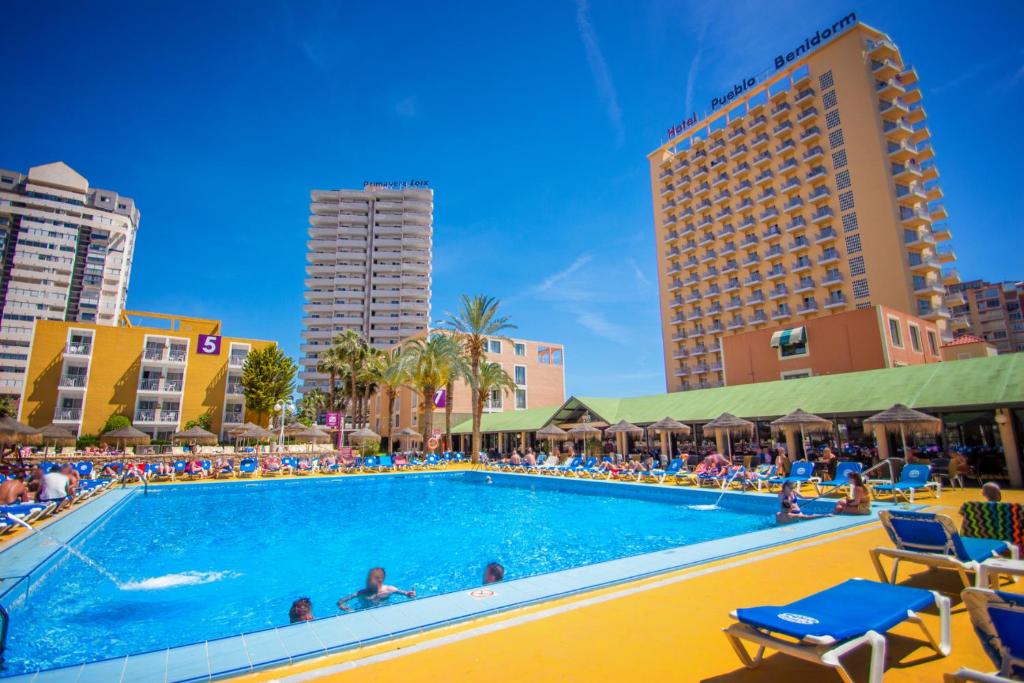 a swimming pool in a hotel with people sitting in chairs at Hotel Servigroup Pueblo Benidorm in Benidorm