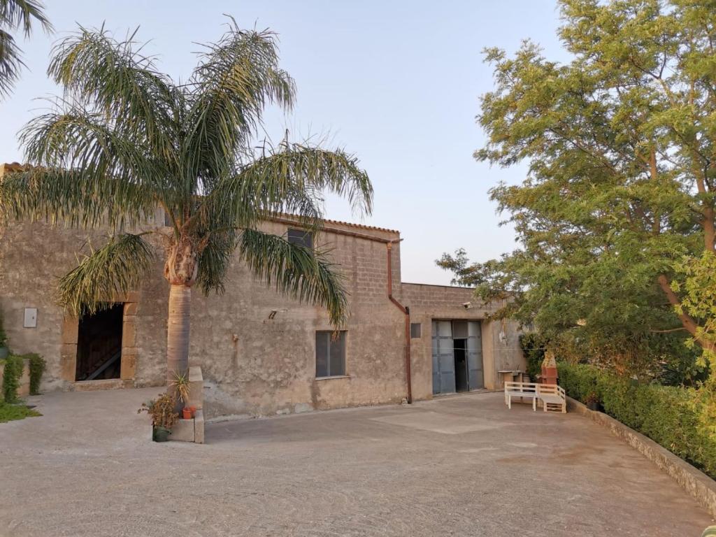 ein Gebäude mit einer Palme davor in der Unterkunft Antico Baglio Siciliano Parecchiata in Buseto Superiore