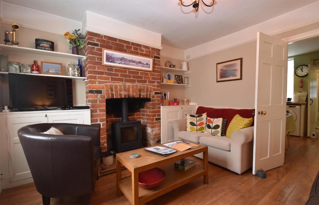 a living room with a couch and a fireplace at Daisy Tatham Cottage in Rye