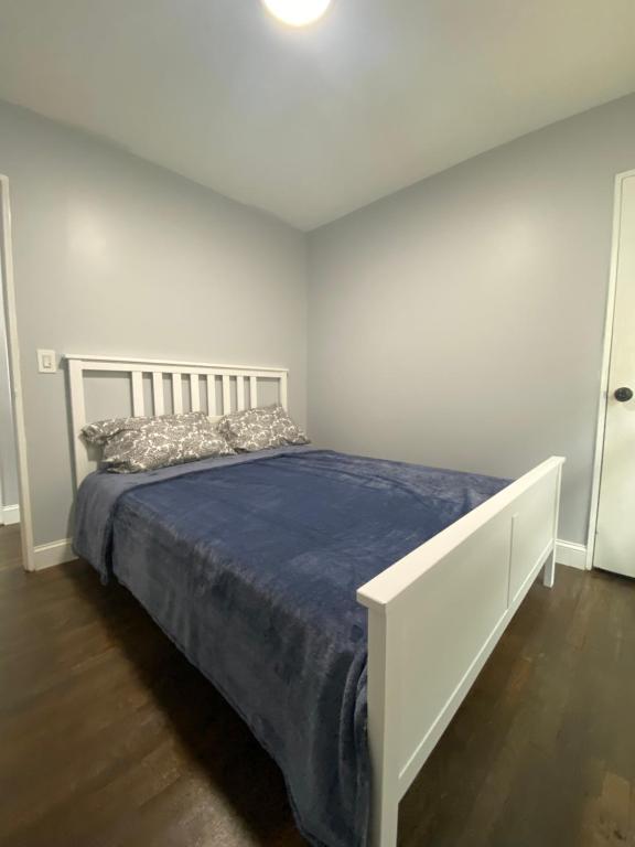 a white bedroom with a bed with a blue blanket at 3 Bedrooms House Nassau County in Hempstead