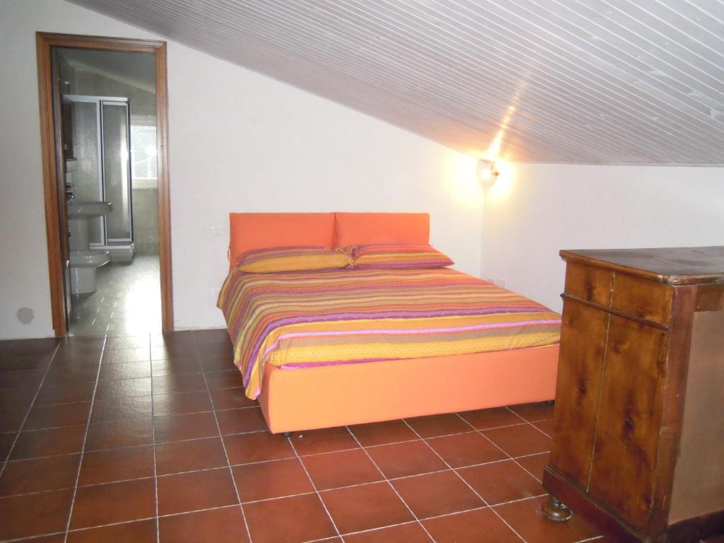 1 dormitorio con cama de color naranja y tocador de madera en I Pettirossi, en Frabosa Sottana