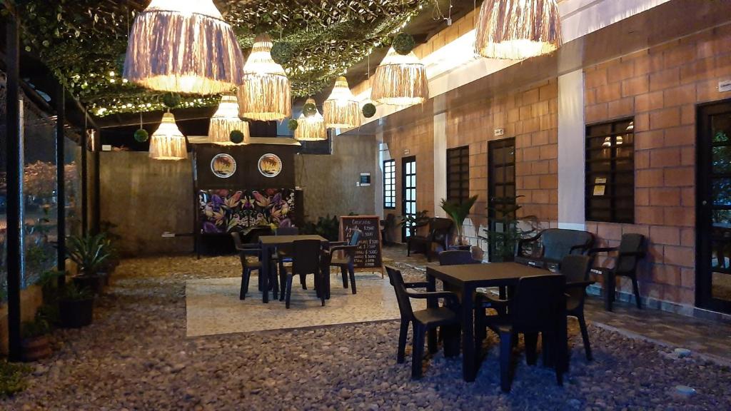 a dining room with tables and chairs and chandeliers at Cabañas Mar Caribe in Necoclí