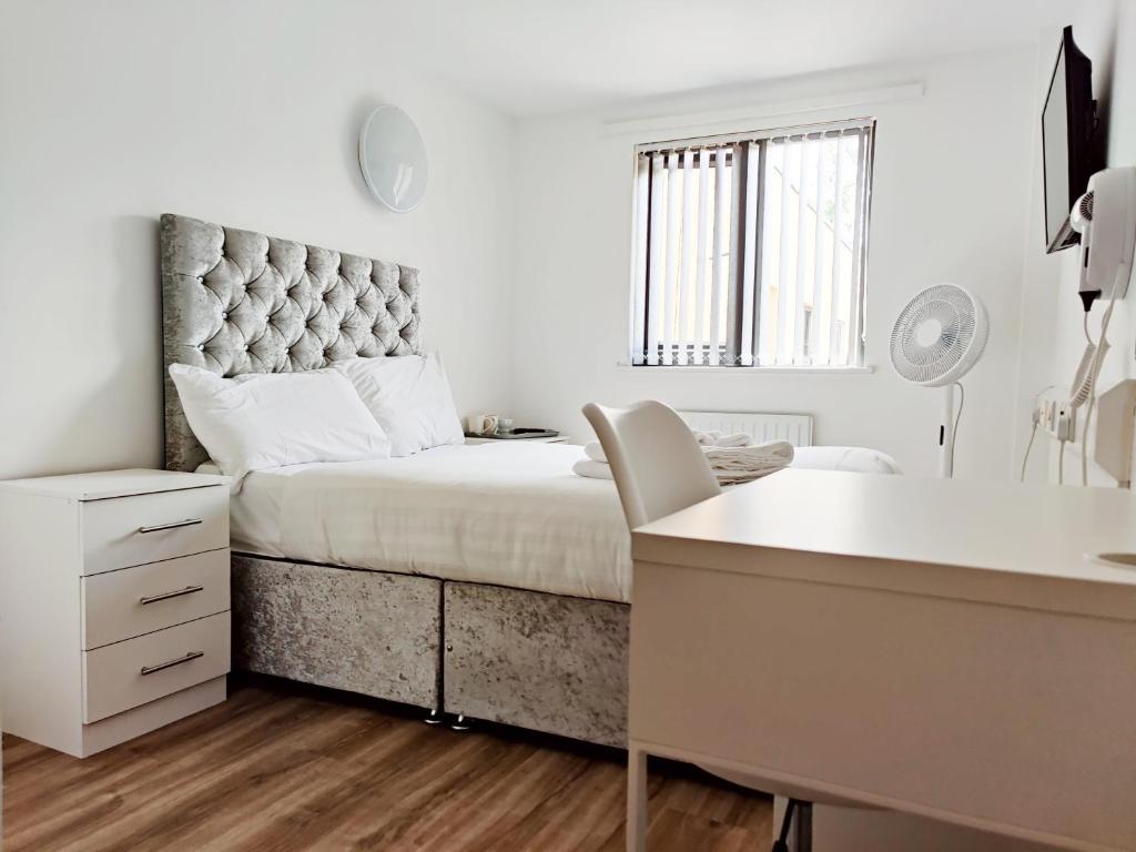 a white bedroom with a large bed with a desk at Accommodation Bradford in Bradford