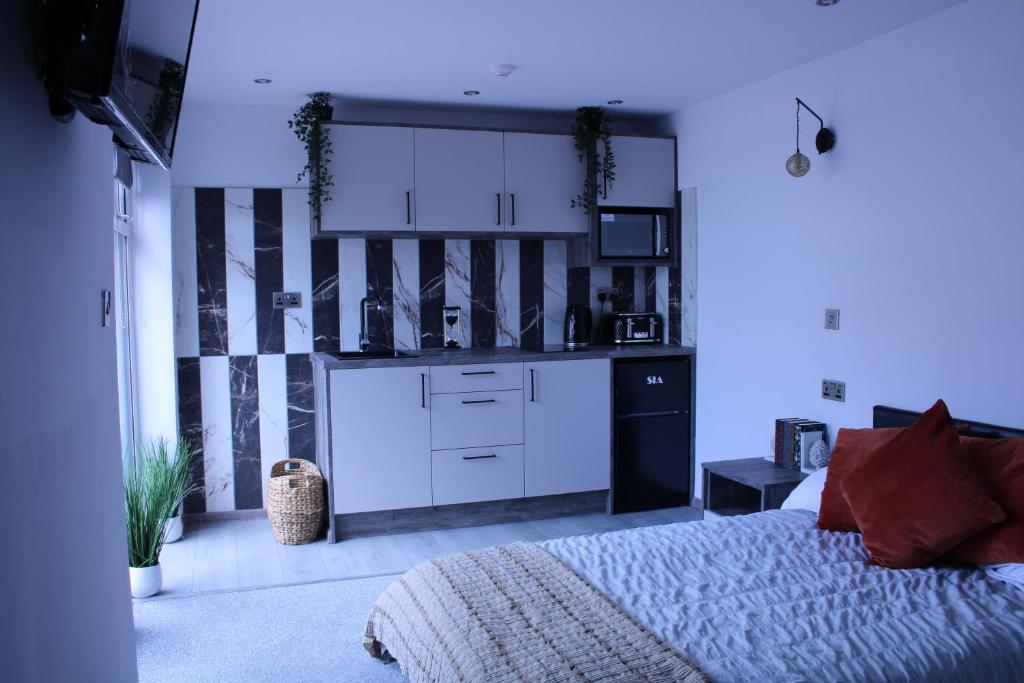 1 dormitorio con 1 cama y cocina con armarios blancos en Private Room perfect for contractor and solo traveler in Peterborough with Kitchenette, en Peterborough