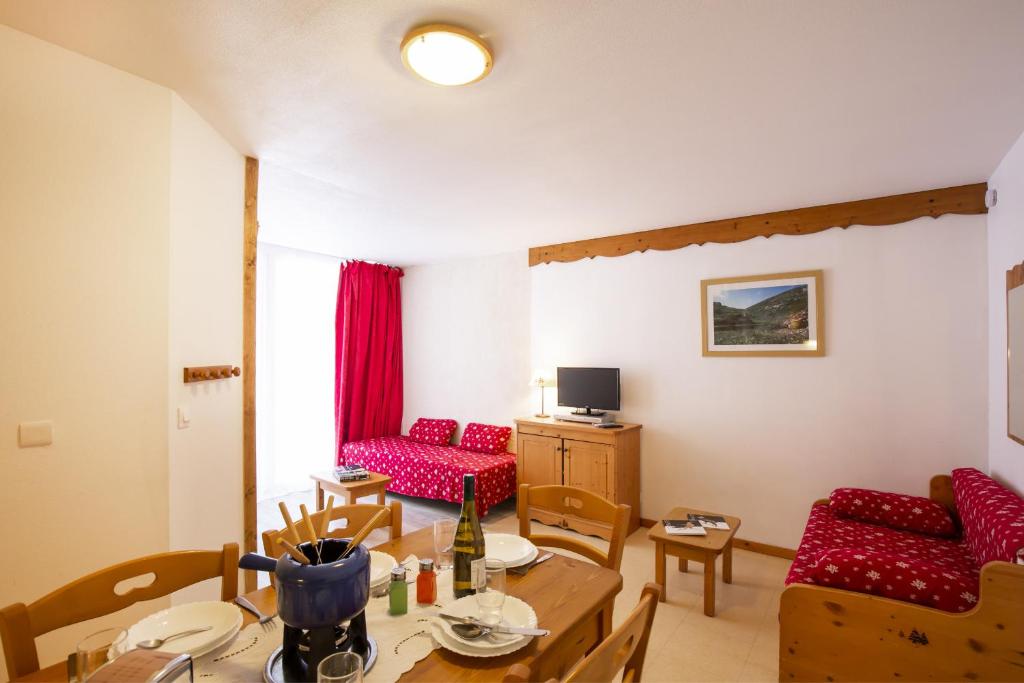 uma sala de estar com uma mesa e cadeiras vermelhas em Les Balcons PROCHE PARC NATIONAL VANOISE studios em Termignon