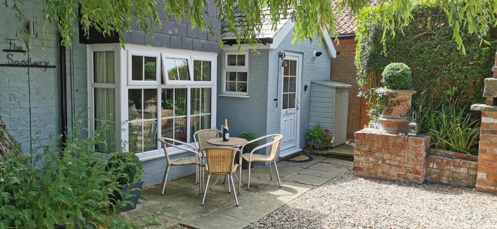 een patio met een tafel en stoelen en een huis bij The Saddlery Holiday Cottage - Near Wolds And Coast in North Thoresby