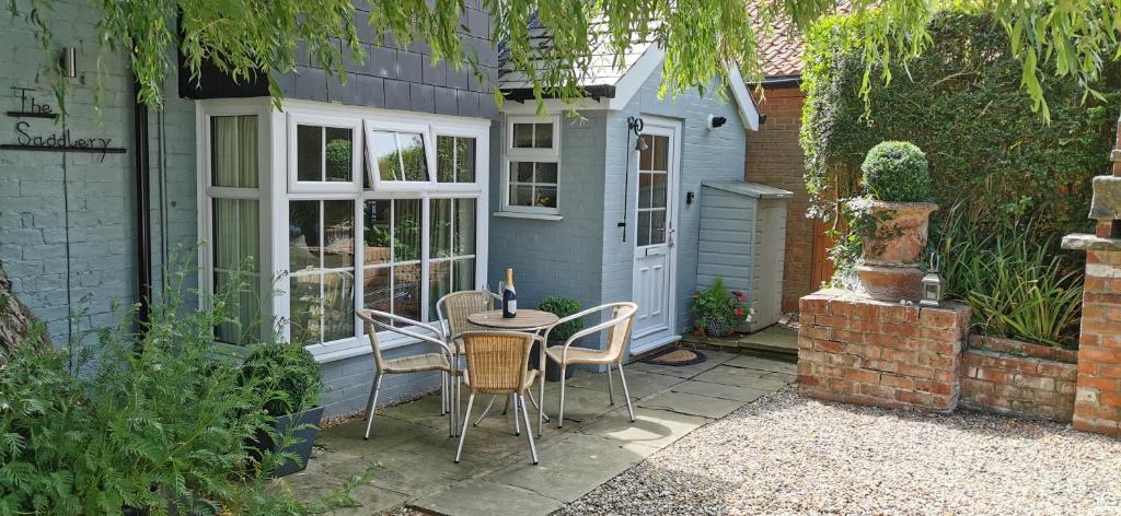 a patio with a table and chairs and a house at The Saddlery Holiday Cottage - Near Wolds And Coast in North Thoresby