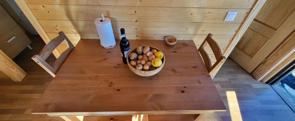 a table with a bottle of wine and a bowl of fruit at Las casitas de Pao in El Pinar del Hierro